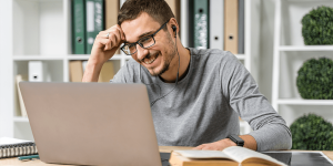 medium-shot-smiley-guy-studying-with-his-laptop-min
